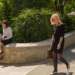 Two girls in a world of their own in the City of London on a sunny day.